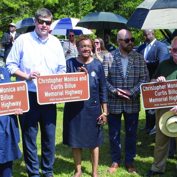 Ocmulgee Judicial Circuit District Attorney T. Wright Barksdale (4th from left, holding sign), Putnam County Sheriff Howard Sills (in green), and State Senator Rick Williams (far right), joined family members of Sgts. Monica and Billue as they received official sign replicas similar to those posted alongside Hwy. 16 in Putnam County. IAN TOCHER/Staff