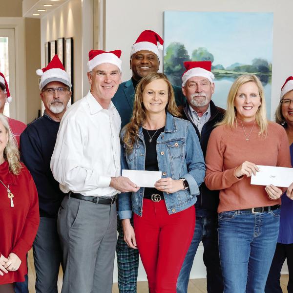 Luxury Lake Oconee’s Ted Baker (center, white shirt) and Weidmann Remodeling’s Dan Weidmann (right, red shirt) present Lake Oconee Area Builders Association’s Wendy Daniel and Christy Kimbrough, alongside team members from both offices, with donations to support LOABA’s Christmas Outreach Drive. CONTRIBUTED