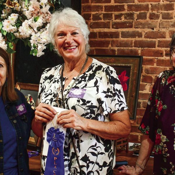 Artist Pat DeVane Burns (center) accepted the blue ribbon, signifying her first-place finish in the 10th annual Lake Country Juried Art Show, from show judge Brenda Pinnick (left) and event co-chair Cathy McIntire. IAN TOCHER/Staff