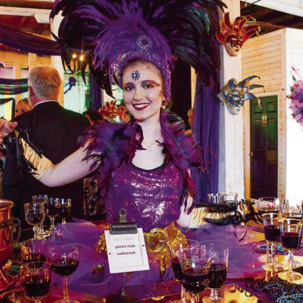 A performer at one of two “living tables” provided wine and ArtiGras beads to guests at The Livery before the party moved next door to Barrel 118. IAN TOCHER/Staff