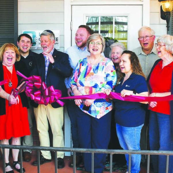 Licensed speech therapist Kay Jones (red dress), owner of Lake Oconee Speech Therapy, cuts the ribbon flanked by her husband and son as other members of her Lake Country community cheer the official opening of her facility at 951 Harmony Rd., Ste. 103, Eatonton. IAN TOCHER/Staff
