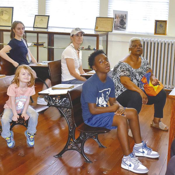 Georgia Benjamin-Smith of Mothers Against Crime tells stories of the past to eager listeners in the old classroom at the Old School History Museum.