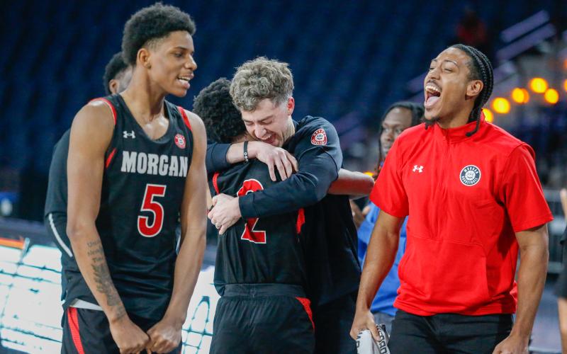 Morgan County head coach Cody Anderson (center) hugs senior point guard Jacoby Simmons (2) after the Dogs defeated Therrell. LANCE MCCURLEY/Staff