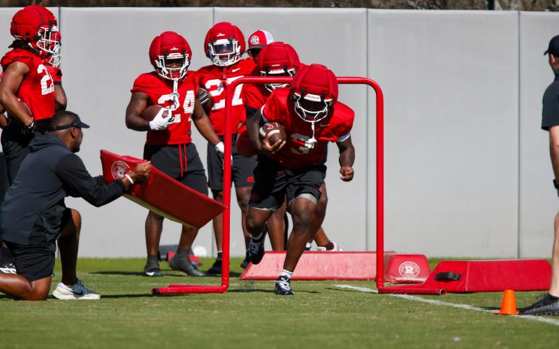 Georgia running back Nate Frazier (3) runs under a chute during a drill at practice, maintaining a low pad level as he drives forward. LANCE MCCURLEY/Staff