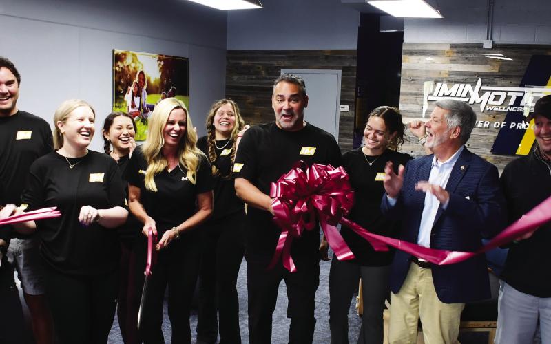 Greene County residents Dana and Dr. Pablo Santamaria (center, with scissors and bow) opened InMotion Wellness initially based on Pablo’s exposure to the benefits of targeted, assisted stretching after undergoing an operation to correct a painful back condition.