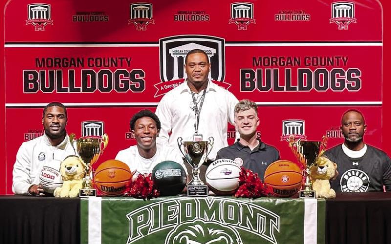 Morgan County senior Zeki Locus (second from left, front row) poses with his coaches after signing with Piedmont University to continue his basketball career. CONTRIBUTED