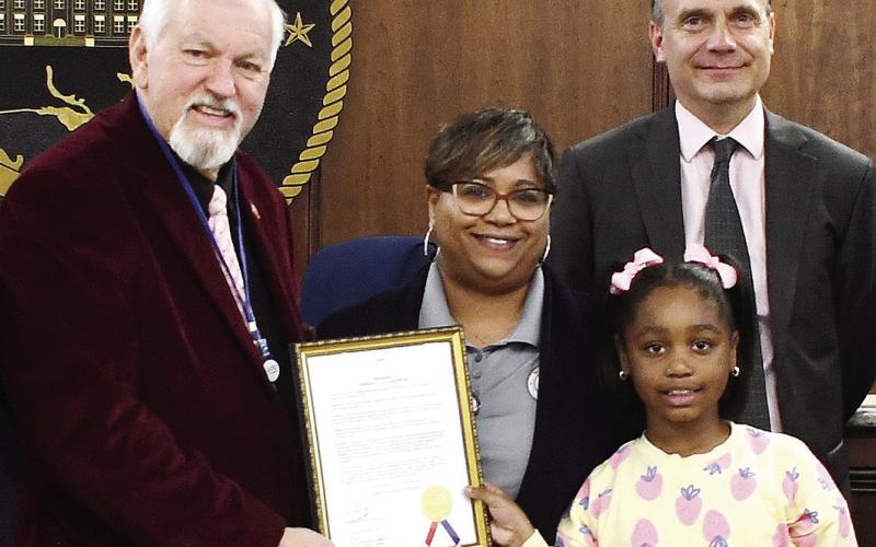L-R: Last Tuesday, County Commission Chairman Bill Sharp awarded County Public Information Officer Stephanie McMullen, with her daughter Reese, an official recognition of Feb. 20 as Government Communications Day, alongside Commissioner Richard Garrett (right) and the rest of the board. IAN TOCHER/Staff