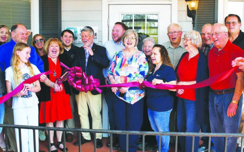 Licensed speech therapist Kay Jones (red dress), owner of Lake Oconee Speech Therapy, cuts the ribbon flanked by her husband and son as other members of her Lake Country community cheer the official opening of her facility at 951 Harmony Rd., Ste. 103, Eatonton. IAN TOCHER/Staff