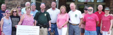 Making a check presentation to fund a bulletproof vest for Greensboro Police’s K9, are, beginning at third from left: 100 Who Care Del Webb Lake Oconee’s Betty Albin, recipient GPD officer Justin Taylor and Koki, Greene County Manager Byron Lombard, GC Safe &amp; Secure Foundation’s Kelley and Charles Middleton, and other members of 100 Who Care Del Webb LO. LYNN HOBBS/Staff