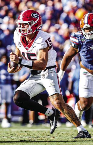 Georgia quarterback Carson Beck (15) shakes a defender in last year’s contest. KARI HODGES/UGAAA