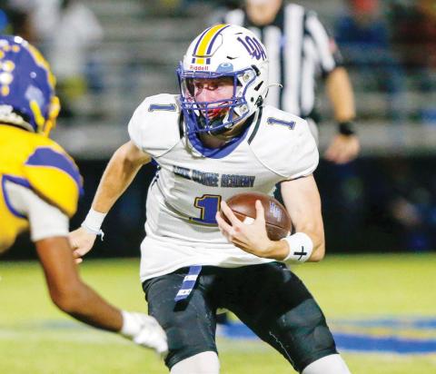 Lake Oconee Academy quarterback Jake McDonald (1) attempts to shake a defender as he tries to pick up a first down with his feet. LANCE McCURLEY/Staff