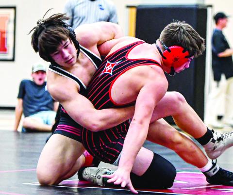 Sophomore Tripp Davis, who placed second in the 165-pound weight division, forces his opponent onto the mat. CHARLES JORDAN/Staff