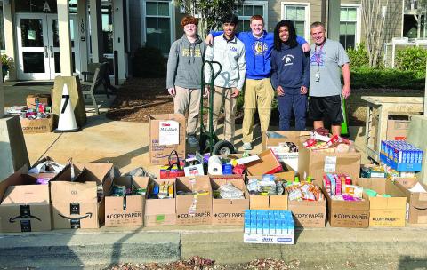 LOA high school students and their weight training teacher Tom Imhoff (far right) collaborated to help load the trucks with several boxes of food for the local pantry. CONTRIBUTED