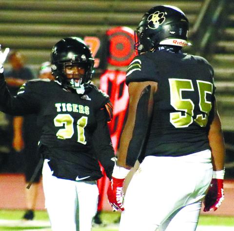 Jailen Ruff (21) and Kevin Wynn (55) high-fiving at midfield after the Tigers’ defense made a play in a game earlier this season. BRENDAN KOERNER/Staff