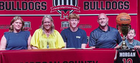 Morgan County basketball’s Justice Lewis (center) poses for a picture with his family during his signing ceremony. CONTRIBUTED