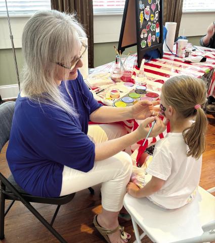 Five-year-old Evelyn Mallinson gets her face painted with a pink flower. (EMMA CLAUSE/Staff)