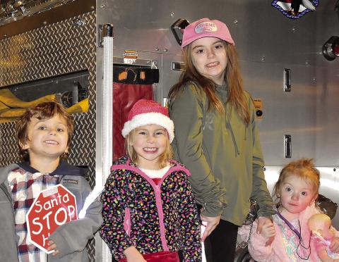 Some of Greensboro’s youngest are all smiles for Christmas while posing in front of a fire truck. HANNAH BARRON/Staff