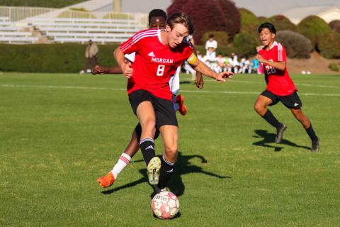 Morgan County’s Scott Chamberlain (8) dribbles the ball away from a Groves’ defender in the first round of the Class AAA playoffs on April 12. LANCE McCURLEY/Staff