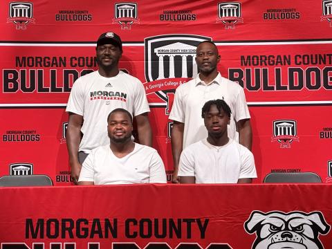 Jaturi Brown (front row - left) and TJ Thomspon (front row - right) with two Morgan County assistant coaches at their signing ceremony on Wednesday, July 12. CONTRIBUTED