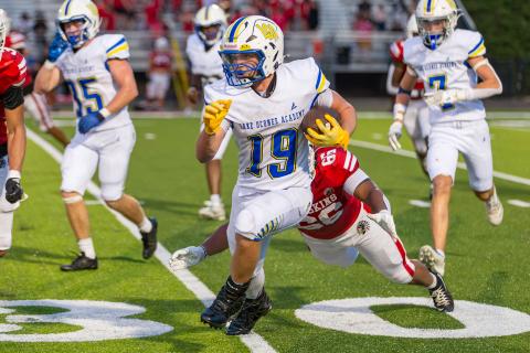 Lake Oconee Academy running back Alden Barreras (19) evades a Social Circle defender during a scrimmage against the Redskins on Aug. 14. SKYLA MORRIS/Staff