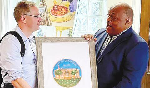 Mayor John Reid (right), presents a framed print of Eatonton City Hall to Mark Libell, chief of staff for Sen. Raphael Warnock. CONTRIBUTED