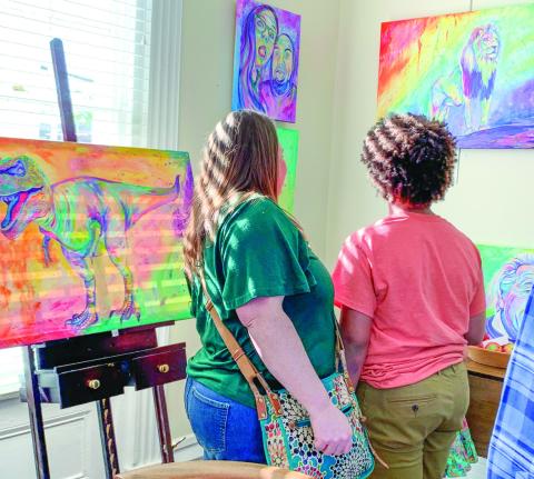 Two attendees view “Chromatic King” (right) that depicts a lion looking out beyond where it stands.