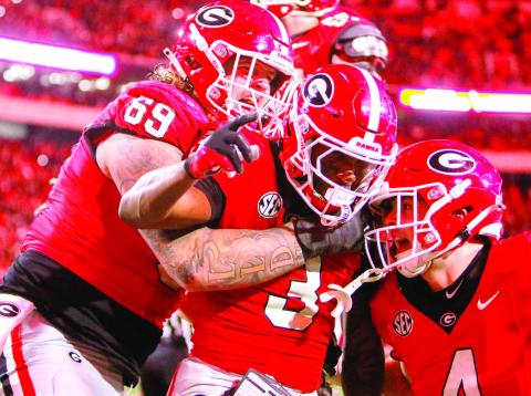 Nate Frazier (3) celebrates with teammates after scoring a game-winning two-point conversion for Georgia during the eighth overtime against rival Georgia Tech. LANCE McCURLEY/Staff