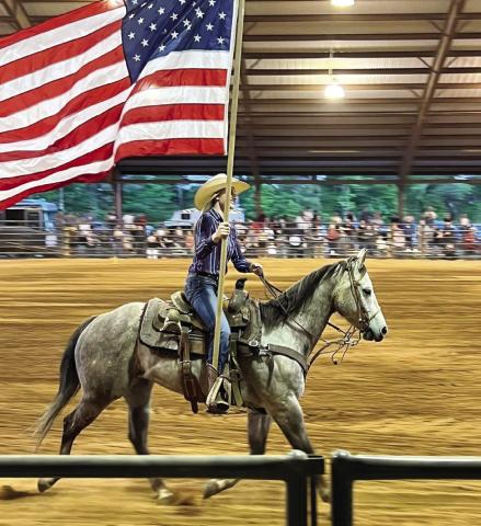 A rodeo performer carries the American flag during the presentation of flags. (CONTRIBUTED)