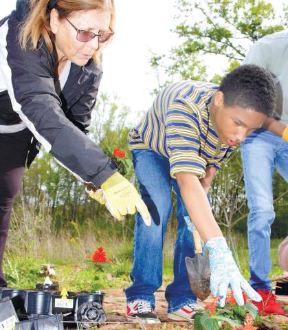 Volunteer Jonna Rubins Marchuk helps an APPLE student plant flowers at the Butterflies and Blooms habitat. IAN TOCHER/Staff