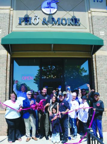 Pho & More co-owner Marino Graf (with scissors) stands with his wife, Summer, her father, John Nguyen, and the couple’s daughter while friends and employees help them celebrate during a ribbon-cutting ceremony hosted by the Eatonton-Putnam Chamber of Commerce. IAN TOCHER/Staff