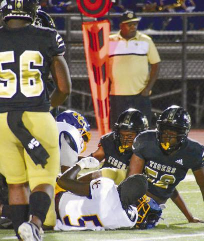 Dayshawn Copeland (52) and other Tiger defenders tackle the Screaming Devils’ running back in the first half. BRENDAN KOERNER/Staff
