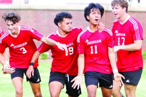 Morgan County sophomore midfielder Brandon Lopez (11) celebrates with teammates Cooper Franklin (3), Santiago Ramirez (19), and Carson Keener (17), after scoring a goal to tie the game with Peach County in last week’s second-round playoff game. (LANCE MCCURLEY/Staff)