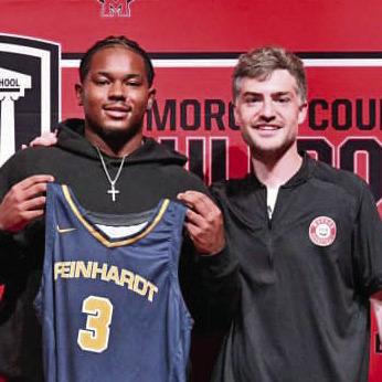 Ryan Moore (left) holding up a Reinhardt University basketball jersey next to Morgan County boys’ basketball coach Cody Anderson (right) at his signing ceremony. (RANDY GREGG/Contributed)
