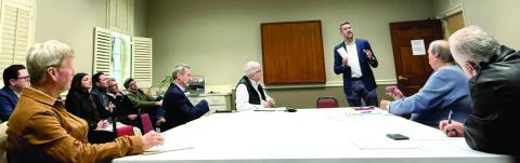Joel Wiggins (standing), managing partner of the Southern Group of Georgia and a representative of the C-PACE Alliance, addresses members of the Lake Oconee Area Development Authority last Thursday at Farmers &amp; Merchants Bank on Lake Oconee Parkway. Melody Echols, program administrator with Peach State C-PACE, is seated at left. IAN TOCHER/Staff