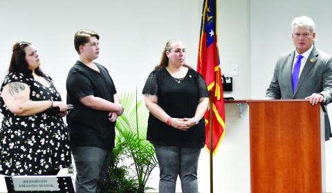 U.S. Rep. Mike Collins (far right) presents the Carnegie Medal to the family of Thomas Hawk: (l-r) daughter MacKenzie Hawk, son Eric Hawk and wife Amanda Hawk. T. MICHAEL STONE/Staff