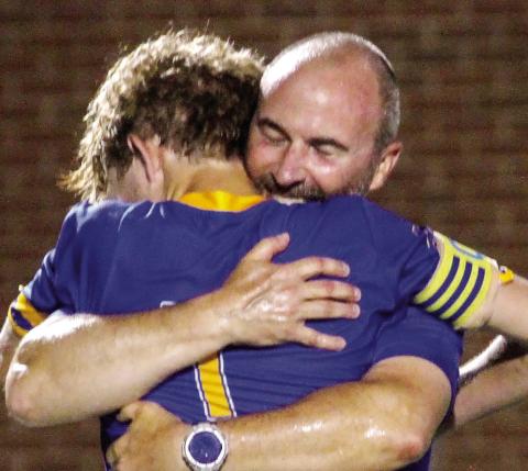 Lake Oconee Academy coach Tyler Mayer hugs senior Palmer Larkin after the Titans won the state title over Atkinson County. BRAD HARRISON/Staff