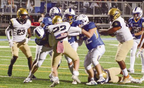 A group of Titans move a Lions defender down the field on the way to a first half touchdown last Friday night. BRENDAN KOERNER/Staff