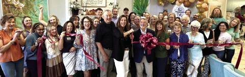 With husband Steve at her back, Compassion Café owner Lisa Tubbs wields the scissors for a ribbon-cutting ceremony arranged by Robbie King (behind bow) of the Eatonton-Putnam Chamber of Commerce. IAN TOCHER/Staff