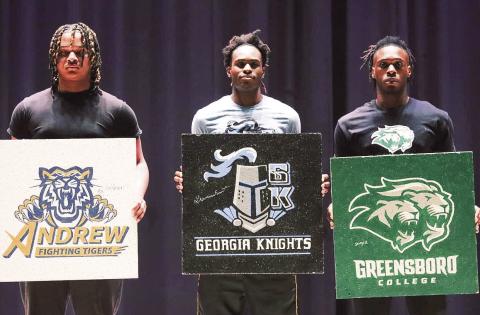 (From L to R): Greene County athletes Jay’shaun Jernigan, Kamari Smith, and Jaquavious Burdette, hold up artwork featuring their colleges during Monday’s signing ceremony. (LANCE MCCURLEY/Staff)