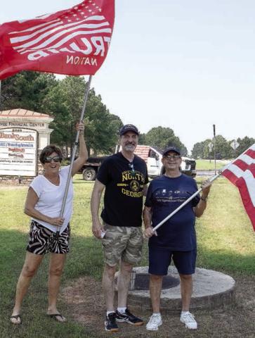 Despite wind and high temperatures, the flag continued to hold high with Gail Hartley, David DuBois and David Lollis. (LEIGH LOFGREN/Staff)