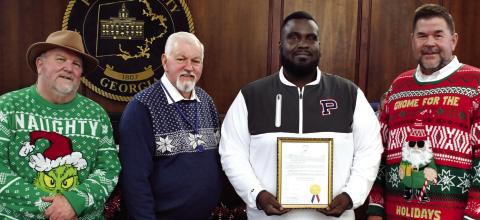On behalf of his fellow coaches and a roster 39 players, Alexander Banks, head coach of the 2025 Putnam County Middle School War Eagles football team, accepted a framed proclamation last Tuesday night recognizing the team’s 2025 state championship from (l-r) Commissioner Jeff Wooten, Chairman Bill Sharp, and Commissioner Tom McElhenney. IAN TOCHER/Staff