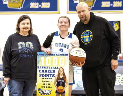 Lake Oconee Academy senior Ansleigh Padgett (middle) stands with her family as she’s honored at midcourt on Tuesday night after scoring her 1,000th-career point. SKYLA MORRIS/Staff