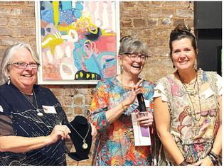 L-R: Art show chairperson Michele Hartung and co-chair Cathy McIntire congratulate The Artisans Village communications specialist Melanie Schneider after she won a Merit Award for “Golden Spiral,” a necklace she designed and created. IAN TOCHER/Staff