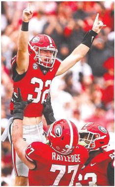 Georgia offensive lineman Tate Ratledge (77) holds up Cash Jones (32) after he scored a touchdown in the fourth quarter of the Bulldogs win over South Carolina last week. TONY WALSH/UGA Athletics