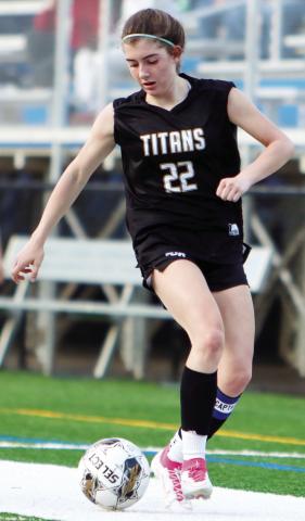 LOA junior midfielder Lauren Glass (22) dribbles the ball away from a GMC Prep defender in a home match on March 12. She’s been a key player for the Lady Titans this year. LANCE McCURLEY/Staff