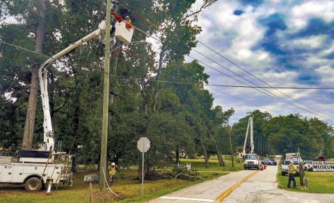 Crews work on downed limbs and power lines at the intersection of North Maple Avenue and Madison Road at the north end of Eatonton. IAN TOCHER/Staff