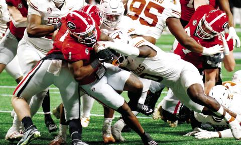 Georgia running back Trevor Etienne (1) fights his way through Texas defenders to score the game-winning touchdown in overtime. LANCE McCURLEY/Staff