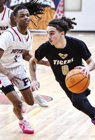 Tigers’ junior Ryder Eschbach (0) takes a baseline-route to the basket against a Putnam County defender. CHARLES JORDAN/Staff 
