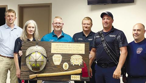 A custom-made commemorative plaque was presented to the retiring chief as part of the retirement reception. Pictured from left to right are: Battalion Chief Dusty Powell, Administrative Assistant Cindy Williams, Chief Jeff Stone, Battalion Chief Josh Tinseth and firefighters Jake Mason and Chris Tuck. T. MICHAEL STONE/Staff
