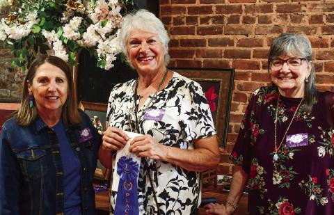 Artist Pat DeVane Burns (center) accepted the blue ribbon, signifying her first-place finish in the 10th annual Lake Country Juried Art Show, from show judge Brenda Pinnick (left) and event co-chair Cathy McIntire. IAN TOCHER/Staff